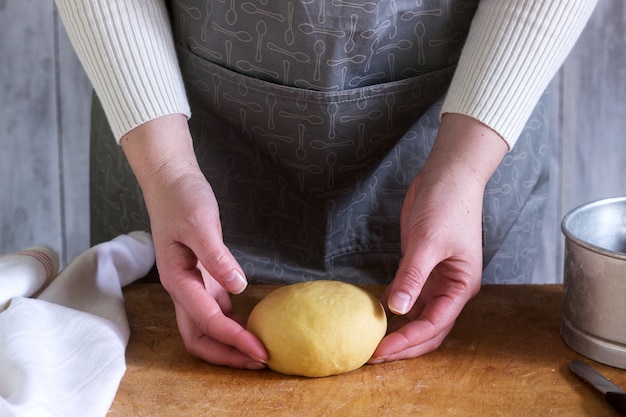 Una donna produce noodles fatti in casa con farina, uova e sale. Stile rustico.