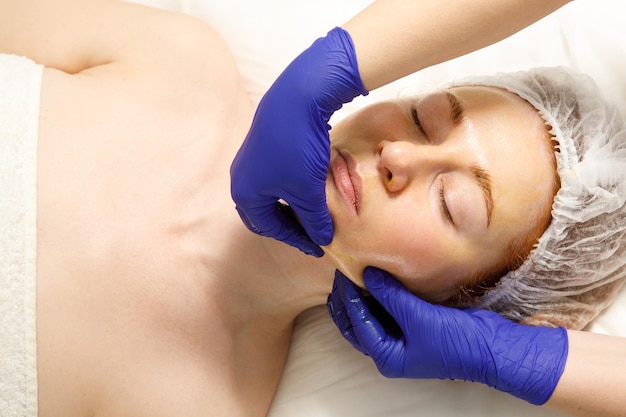 Una donna riceve un massaggio facciale in una clinica di cosmetologia