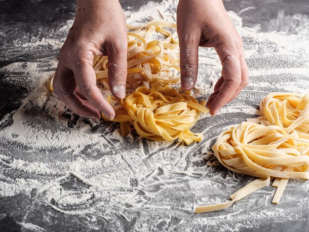 Una donna rotola le fettuccine italiane fatte in casa.