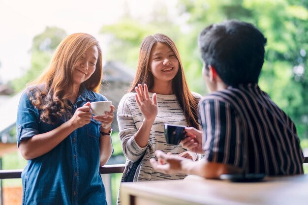 Una donna saluta e saluta i suoi amici maschi mentre beve un caffè