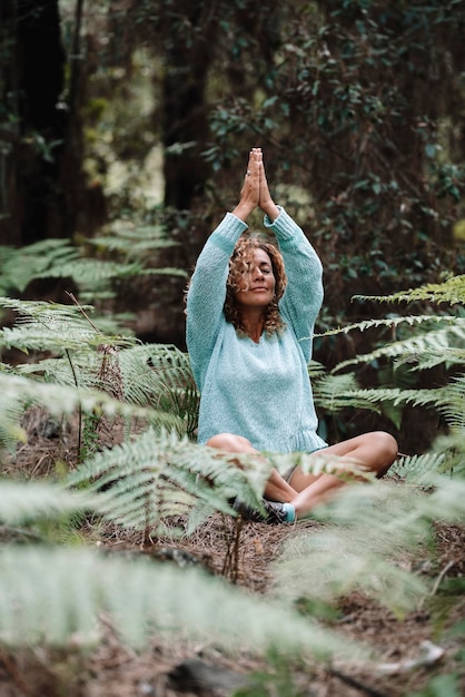 Una donna sana e naturale medita fine pratica esercizio di yoga nei boschi verdi della foresta godendo di attività ricreative all'aperto nella natura Benessere ed esercizio consapevole persone al di fuori Le persone meditano