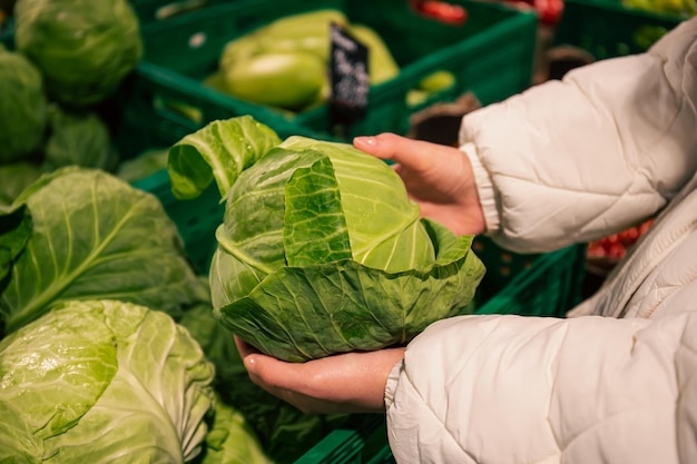 Una donna sceglie il cavolo in un primo piano di un negozio di alimentari