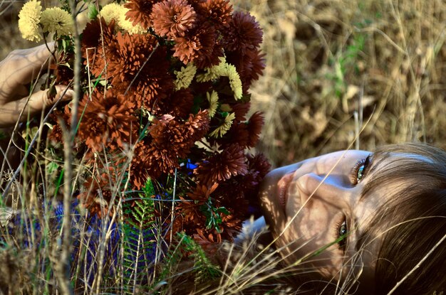 Una donna sdraiata in un campo con un mazzo di fiori sul viso.