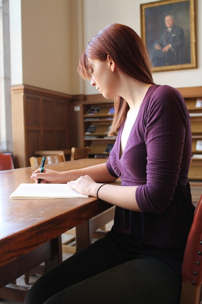 una donna seduta a un tavolo che scrive in un libro.