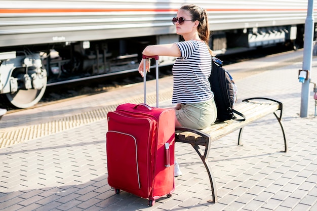 Una donna seduta alla stazione dei treni e in attesa del viaggio