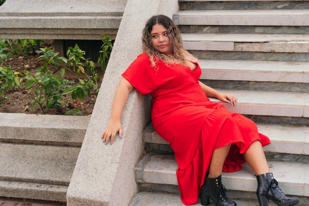 Una donna seduta nel parco che si gode la vita. Una giovane donna sovrappeso in un vestito elegante. Bellezza naturale