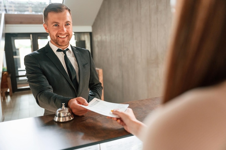 Foto una donna serve un visitatore un uomo con una giacca nera alla reception dell'hotel