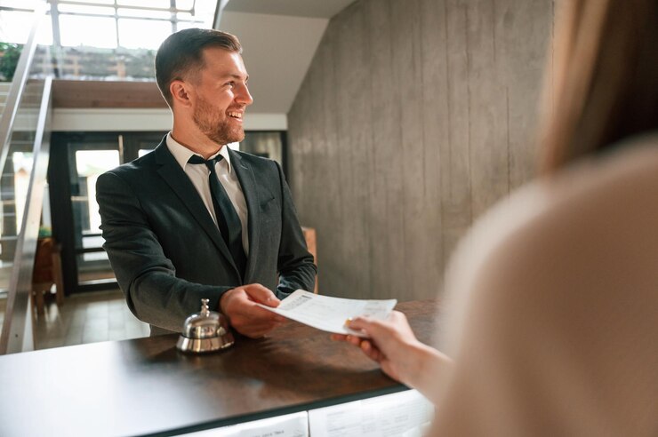 Foto una donna serve un visitatore un uomo con una giacca nera alla reception dell'hotel