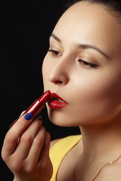 Una donna si dipinge le labbra con un rossetto rosso.
