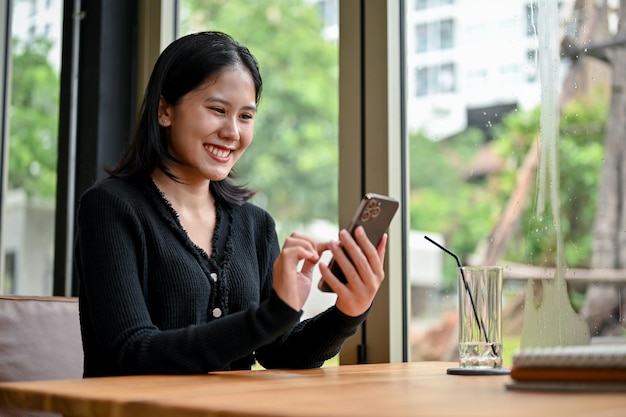 Una donna si diverte a chattare con i suoi amici al telefono mentre si rilassa al bar