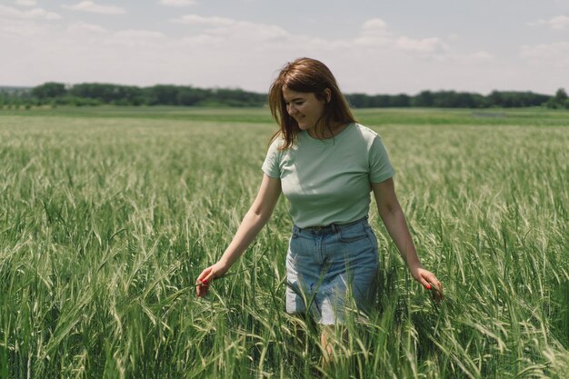 Una donna si gode l'aria fresca della natura in un campo di orzo verde Campagna estiva e raccolta di fiori Atmosfera tranquilla momento