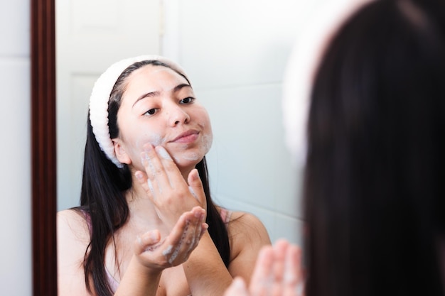 Una donna si guarda allo specchio e applica una faccia asciutta.