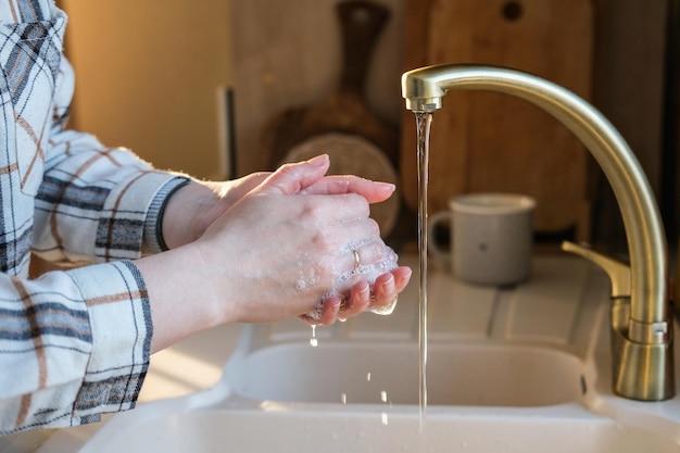 Una donna si lava le mani in cucina prima di cena Igiene personale Lavaggio delle mani