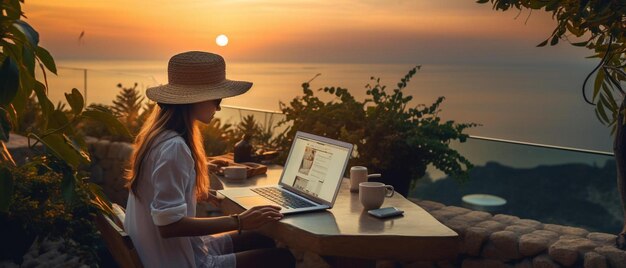 una donna si siede a un tavolo con un laptop e il tramonto sullo sfondo