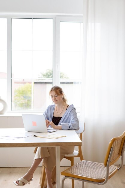 una donna si siede a una scrivania con un portatile e un libro