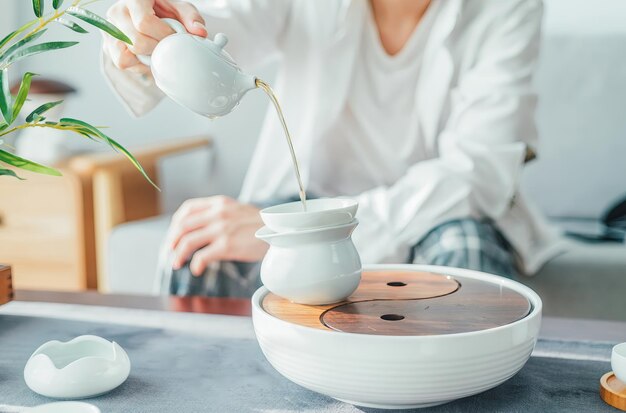 Una donna si siede su un divano e versa acqua calda in una tazza da tè Arte minimalista di fare il tè