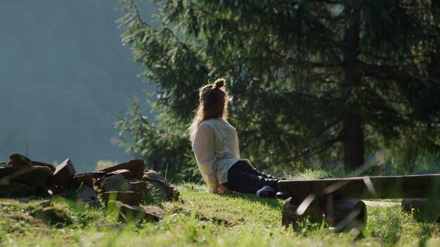 Una donna si siede su una collina in montagna e guarda la telecamera.