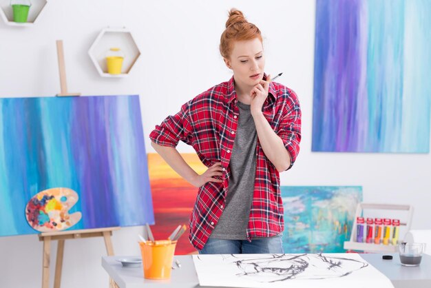 Una donna si trova davanti a un dipinto in uno studio.