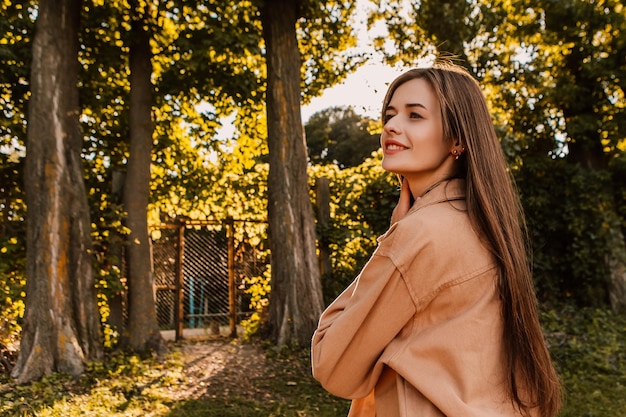 Una donna si trova in un parco in autunno con un albero sullo sfondo