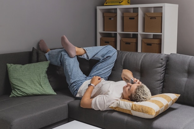 Una donna si trova su un divano con uno smartphone in un interno di casa minimalista