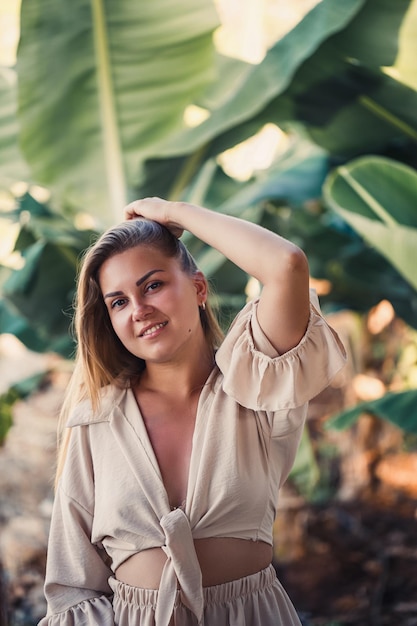 Una donna si trova vicino a foglie di banana verde sull'isola Alberi tropicali