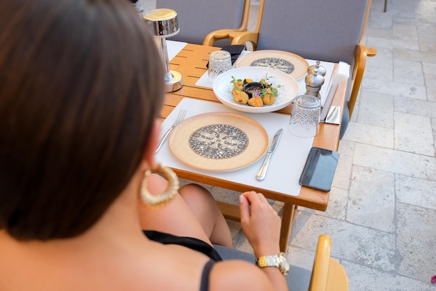 Una donna siede a un tavolo con piatti di cibo e un piatto di cibo.