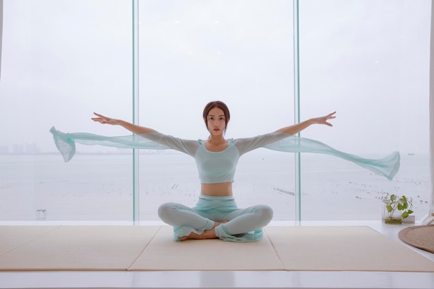 Una donna siede in uno studio di yoga con le braccia tese e le braccia tese.