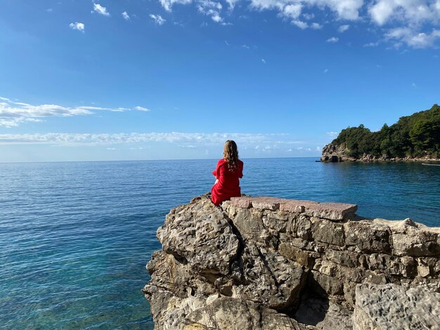 Una donna siede su una roccia a picco sul mare