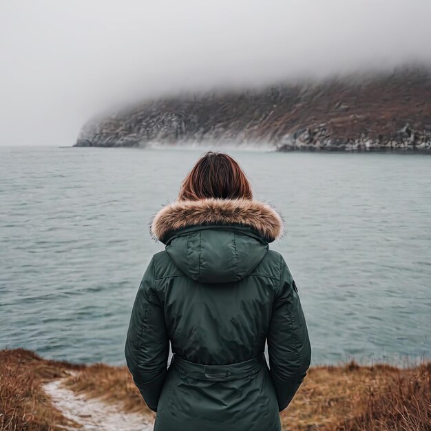 Una donna sola che guarda il mare in una giornata nebbiosa