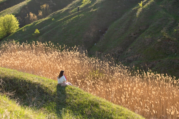 Una donna sola gode del silenzio e della bellezza della natura, seduta su una collina in un luogo pittoresco