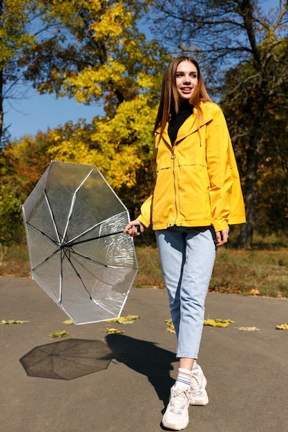 Una donna sorride emotivamente con un ombrello in autunno durante una passeggiata. avvicinamento. autunno