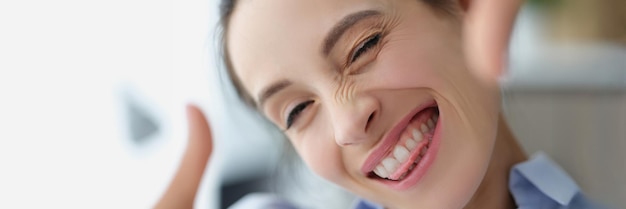 Una donna sorridente felice fa una cornice per foto con le mani insegnando ritratti di alta qualità