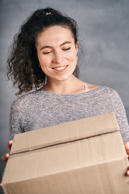 Una donna sorridente felice ha ricevuto una grande scatola che teneva tra le mani