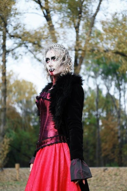 Una donna sotto forma di vampiro o strega con un corsetto e una lunga gonna rossa