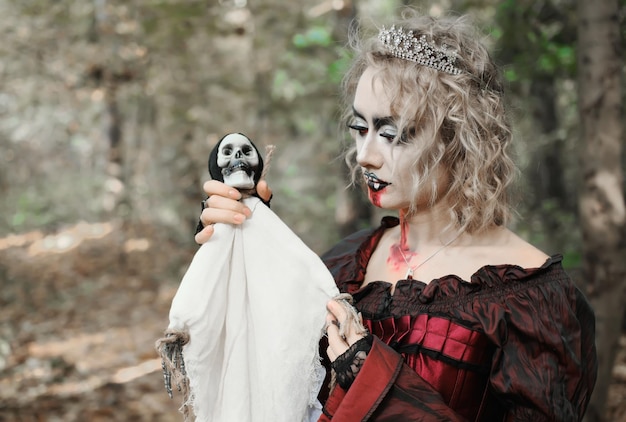 Una donna sotto forma di vampiro o strega tiene tra le mani una bambola sotto forma di morte