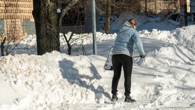 Una donna spala la neve da una strada.