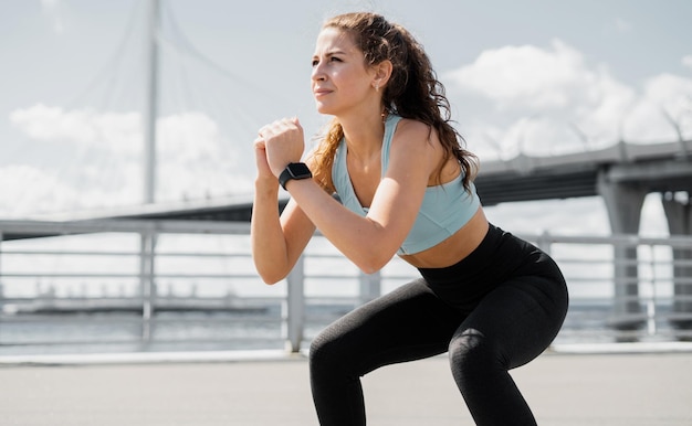 Una donna sportiva fa esercizi di fitness per strada un orologio intelligente sul braccio per l'allenamento