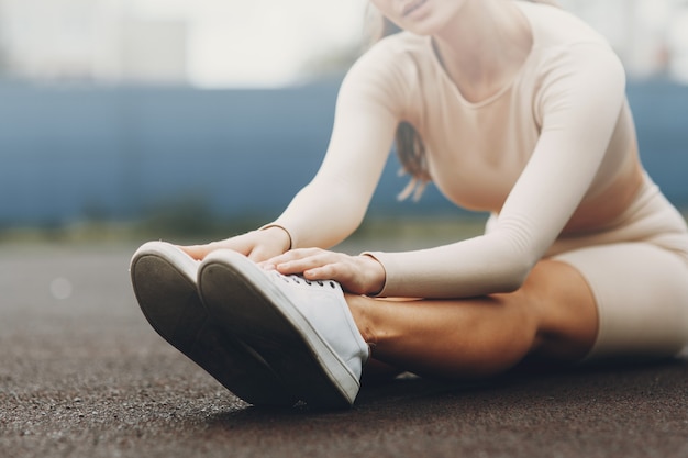 Una donna sportiva si allena e si allena in uno stadio fitness. Riscaldamento all'aria aperta, stretching.