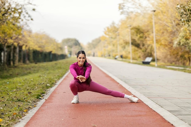 Una donna sportiva sta allungando le gambe sulla pista da corsa.