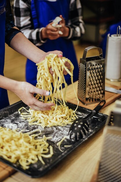 Una donna sta cuocendo la pasta in padella con una grattugia.