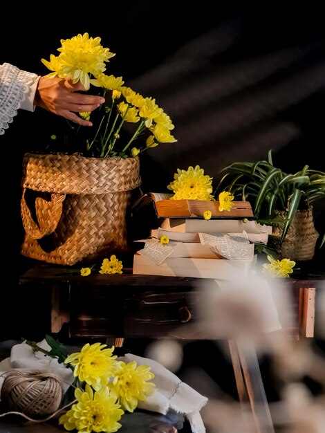 Una donna sta disponendo dei fiori in un cesto su un tavolo.