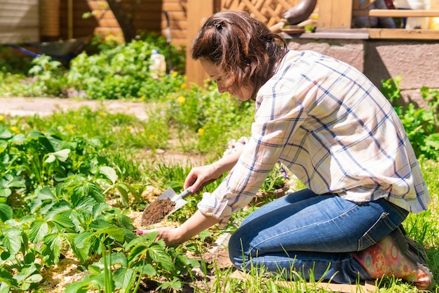 Una donna sta facendo giardinaggio nel suo cortile e pianta piantine