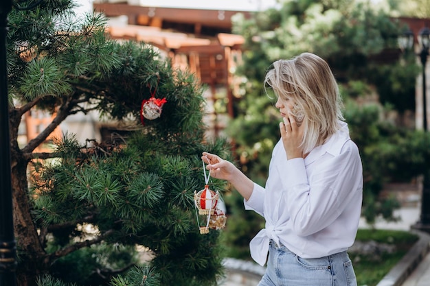 Una donna sta parlando al telefono e vestendo un albero di Natale nel cortile di casa sua