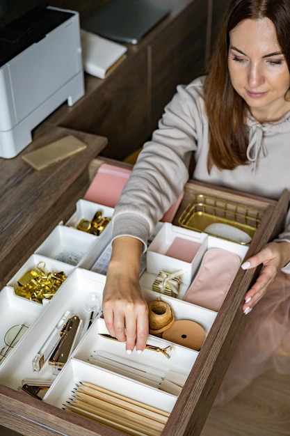 Una donna sta ripulendo il suo posto di lavoro bianco, metodo di conservazione della cancelleria d'oro ben organizzato