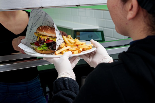 Una donna sta servendo un hamburger e patatine fritte