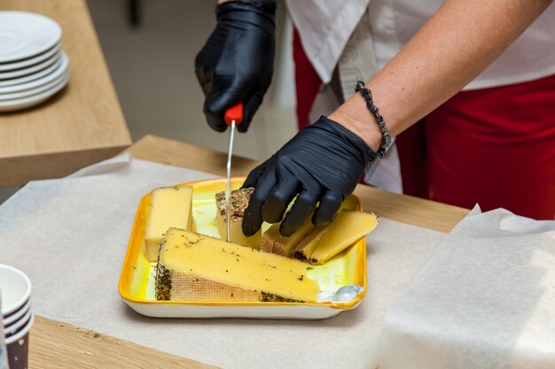 Una donna sta tagliando pezzi di formaggio con un coltello su un piatto giallo per la presentazione