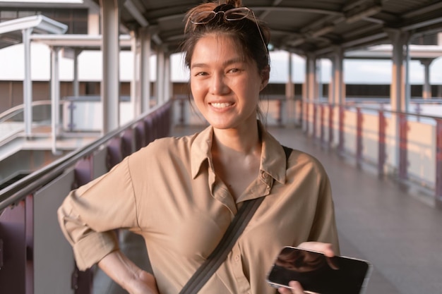 Una donna sta usando il telefono cellulare sul ponte della città di Bangkok