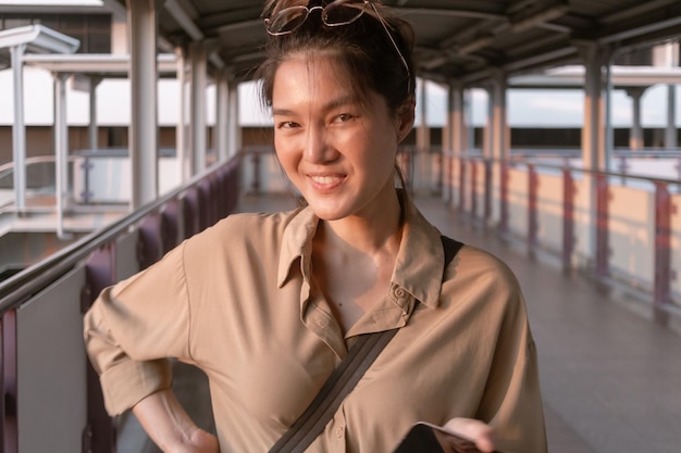 Una donna sta usando il telefono cellulare sul ponte della città di Bangkok