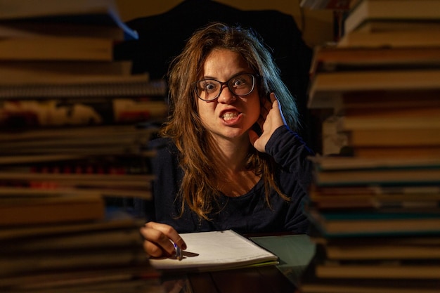 Una donna stressata che studia in una biblioteca per gli esami finali