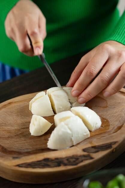 Una donna taglia la mozzarella per l'insalata